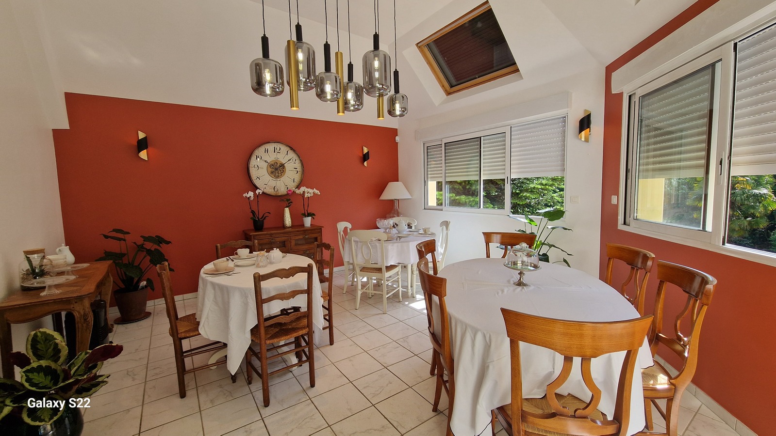 La salle de petit-déjeuner, son mur terracotta et ses tables nappées de blanc