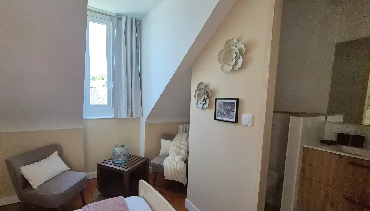 Coin repos de la chambre Lune : deux fauteuils gris et une table basse en bois sombre sous la pente du toit