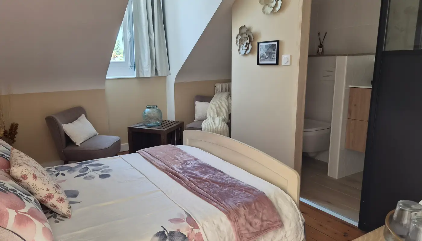 Chambre Lune sous les combles, très grand lit double, fauteuil gris et salle d'eau ouverte à droite