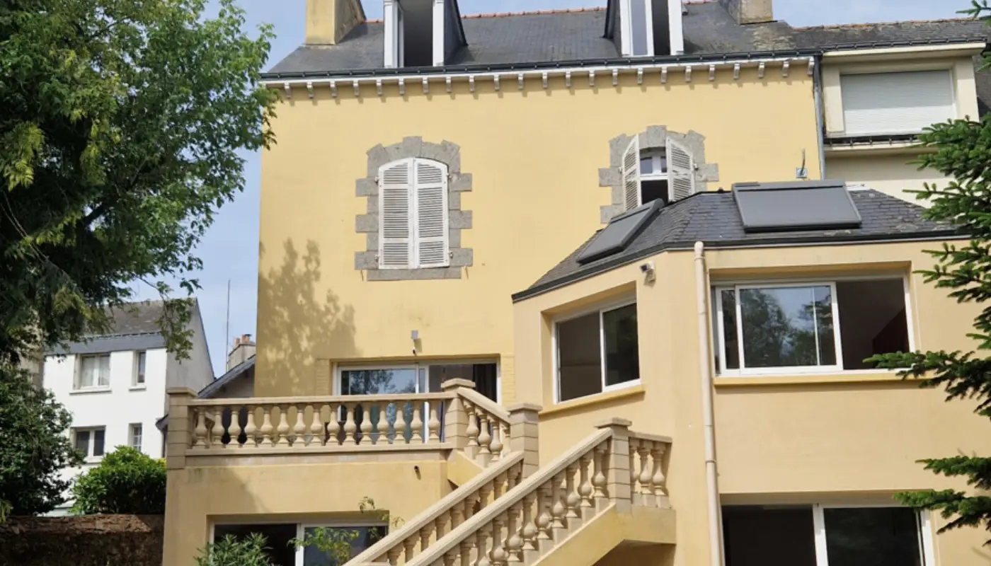 Façade ocre de la maison, son escalier de pierre à balustres et sa toiture d'ardoise