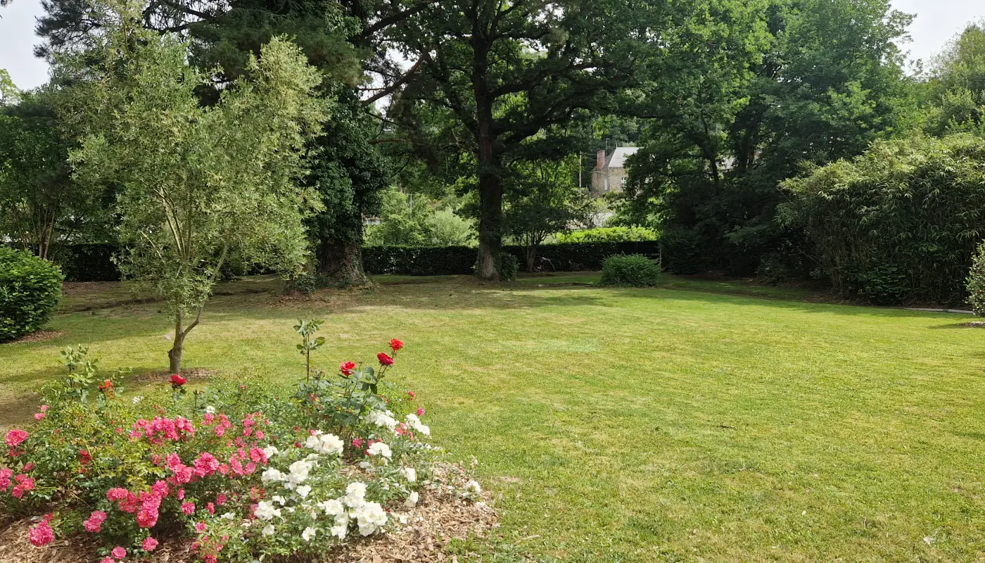 Le jardin, sa grande pelouse, ses massifs de rosiers et ses arbres anciens