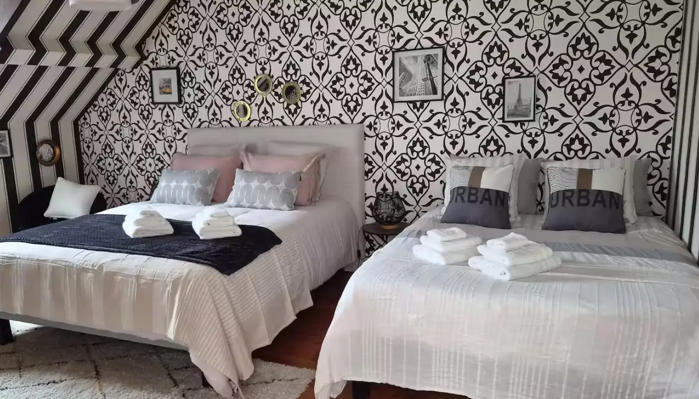 Chambre familiale Papillon avec ses deux grands lits doubles, papier peint graphique noir et blanc et parquet ancien